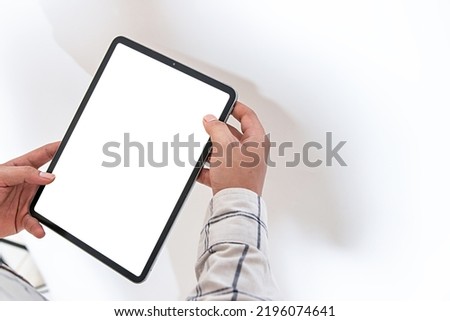 An image with a man holding a white blank screen tablet for mockup