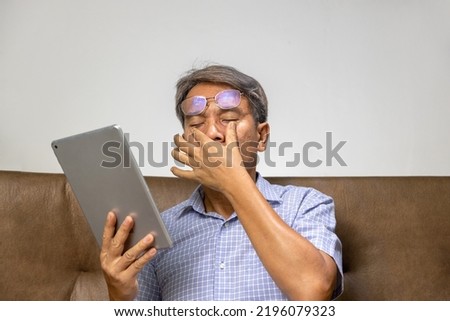 Senior asian man has eyestrain and fatigue Royalty-Free Stock Photo #2196079323