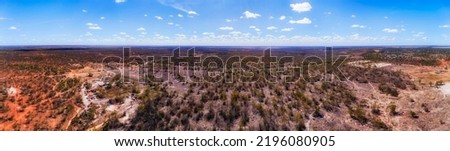 Opal mine shafts on red soil plains around Lightning Ridge regional town in NSW of Australia - aerial panorama.