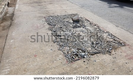 Cracked concrete road surface. Cement roads damaged by drilling rectangular shapes to lay urban underground drainage and power lines with copy spaces. selective focus  Royalty-Free Stock Photo #2196082879
