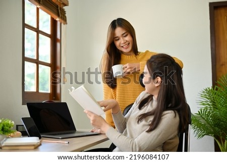 Two attractive young Asian female college students happy to do project together, enjoys chatting during discuss their school project at home.