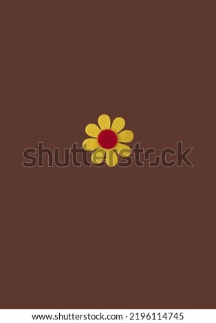 Simple isolated yellow flower on brown background. Minimal happiness concept with copy space. Flat lay.