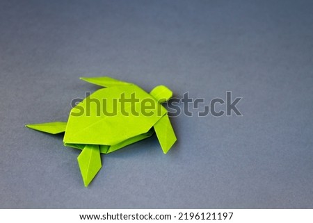 Green paper turtle origami isolated on a blank grey background