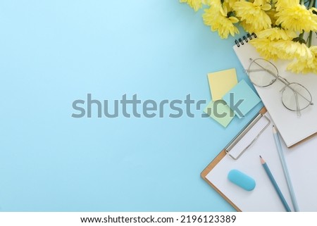 Beautiful flowers and stationery on light blue background, flat lay with space for text. Teacher's Day