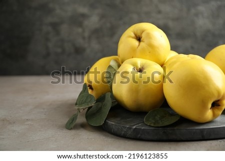 Fresh ripe organic quinces with leaves on grey table. Space for text