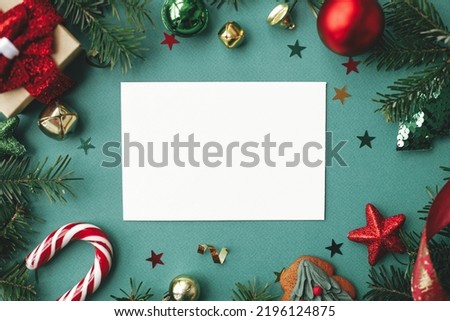 Christmas card mock up. Modern greeting card flat lay with stylish christmas decorations and fir branches on green background. Empty postcard template with space for text. Merry Christmas!