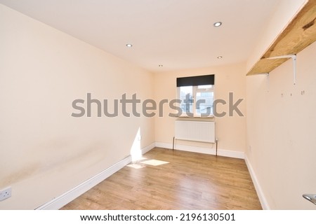 Empty unfurnished bedroom with magnolia painted walls and laminated wood flooring in London UK