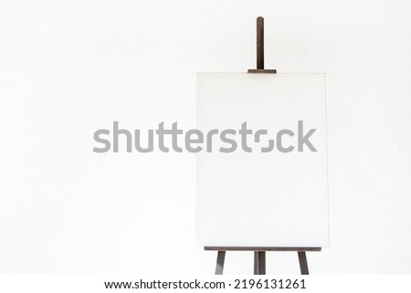 Wooden easel with blank canvas on light background for mockup design
