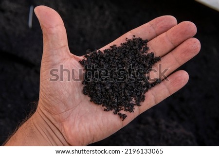 Recycled rubber in hand. Rubber crumb obtained in the process of recycling used car tires used for flooring sports and playgrounds. Royalty-Free Stock Photo #2196133065