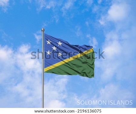 The National flag of Solomon Islands blowing in the wind in front of a clear blue sky.  