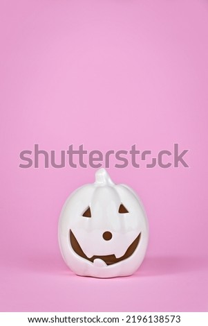 Pumpkin decoration with face on pink background with copy space