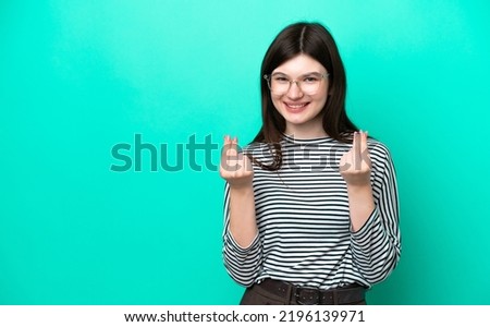 Young Russian woman isolated on green background making money gesture