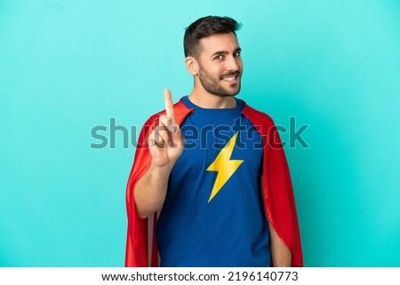 Super Hero caucasian man isolated on blue background showing and lifting a finger Royalty-Free Stock Photo #2196140773