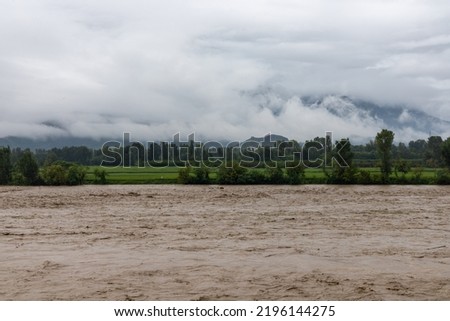Swat river flood after heavy rain, agriculture land submerged under flood water during monsoon season with white clouds on background Royalty-Free Stock Photo #2196144275