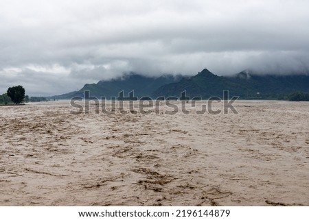 Flooded river submerging the valley after heavy rain Royalty-Free Stock Photo #2196144879