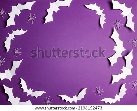 Halloween flat lay composition with white bats and spiders on purple background. Happy halloween banner mockup. Flat lay, top view, copy space.