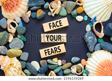 Face your fears and support symbol. Concept words Face your fears on wooden blocks. Beautiful black background. Sea stones and sea shells. Business and Face your fears quote concept. Copy space.