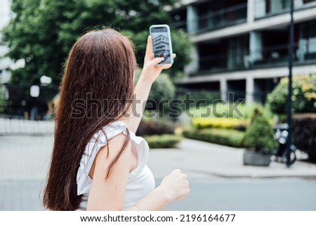 Woman taking picture of the new house with mobile phone. Homebuyer using smartphone to photograph the apartment