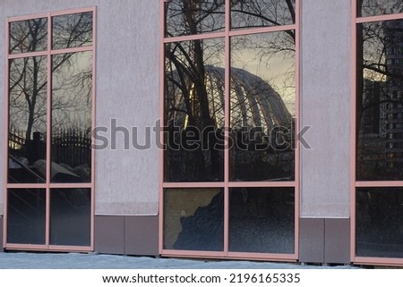 Full-color horizontal photo. Geometric composition with a part of the facade of the building. The windows reflect the city landscape.