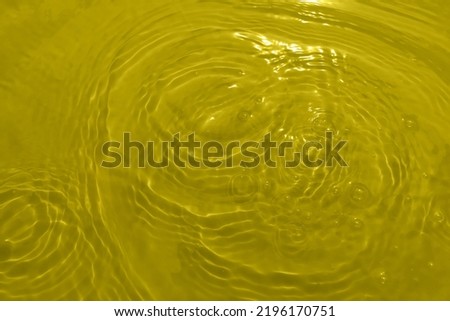 Defocus blurred transparent yellow colored clear calm water surface texture with splashes and bubbles. Trendy abstract nature background. Water waves in sunlight with copy space.  Yellow water shining