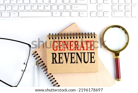 GENERATE REVENUE text in office notebook with keyboard, magnifier and glasses , business concept