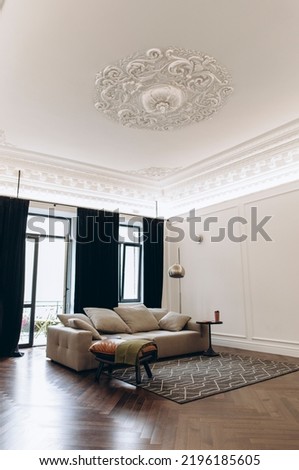 an example of a living room interior in a neo-classical style with modern elements. a sofa in the middle of a room with high ceilings and moldings. Royalty-Free Stock Photo #2196185605