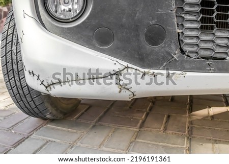 Metal rivets on a cracked car bumper.Old broken car bumper with metal wire Royalty-Free Stock Photo #2196191361