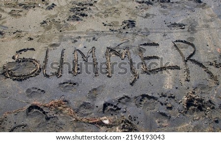 Word summer written on black sand at sea beach, summer time