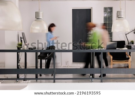 Diverse employees silhouettes walking in business coworking space, long exposure effect. Blurred busy professional workers, start up office staff workday, work rush concept, wide shot Royalty-Free Stock Photo #2196193595