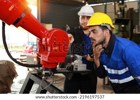 Professional heavy industry technician engineer in safety workwear and businessman maintenance and check part of robot arm machine with tablet in factory automotive. Industrial and technology concept