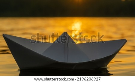 Paper boat on the background of sunset. Background picture.