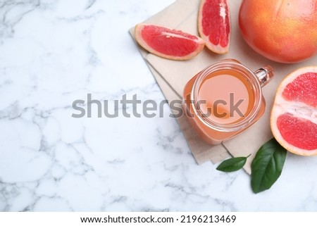 Tasty freshly made grapefruit juice and fruits on white marble table, flat lay. Space for text