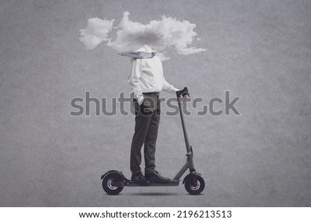 Businessman riding an electric scooter with his head in a cloud: isolation, distraction and mental fog concept Royalty-Free Stock Photo #2196213513
