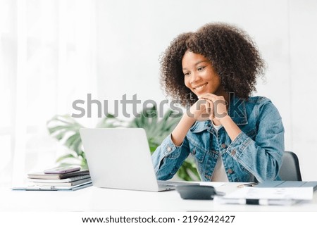 American teenage woman sitting in white office with laptop, she is a student studying online with laptop at home, university student studying online, online web education concept.