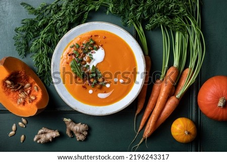 Vegetarian autumn pumpkin and carrot soup with cream, spicy chickpeas and radish micro greens. Comfort food, fall and winter healthy slow food 