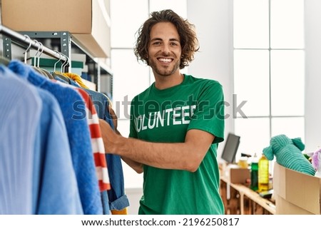 Young hispanic volunteer man smiling happy working at charity center.