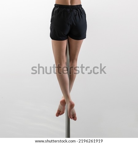 Vertical photo of sporty female legs without shoes climbing the pylon for pole dance on white background