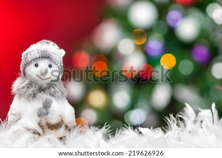 Cute dressed up snowman standing in the snow. Christmas tree as a background.
