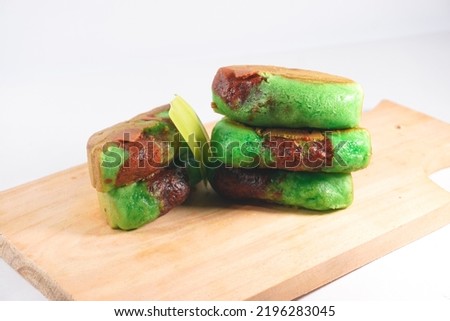 Green Pandan Pukis Cake. Popular Traditional Snack in Indonesia or Jajan Pasar. Served in a clean wooden board on a white background.