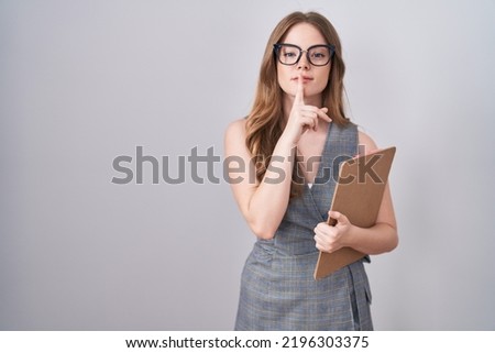 Caucasian woman wearing glasses and business clothes asking to be quiet with finger on lips. silence and secret concept.  Royalty-Free Stock Photo #2196303375