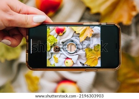 Hands with a phone take pictures of the autumn composition. The blogger makes a video. Photo of food using a smartphone in a home studio.