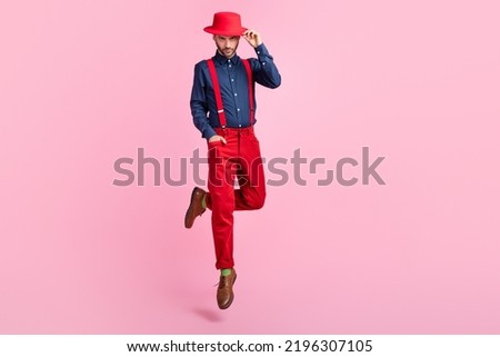 Full length portrait of rich confident young man jumping hand touch hat isolated on pink color background Royalty-Free Stock Photo #2196307105