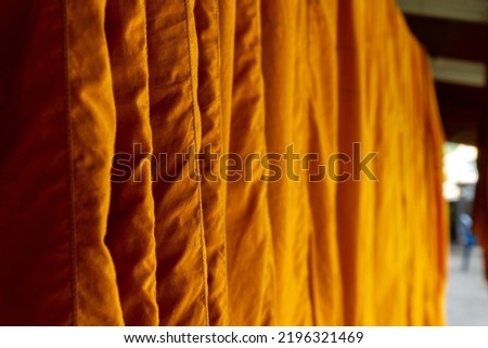 orange robe of a buddhist monk or novice hanging under the building