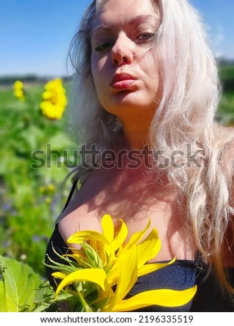 Beautiful womans face in sunglower fields holding sunflower long natural hair blue sky nature lover holiday natural  Royalty-Free Stock Photo #2196335519