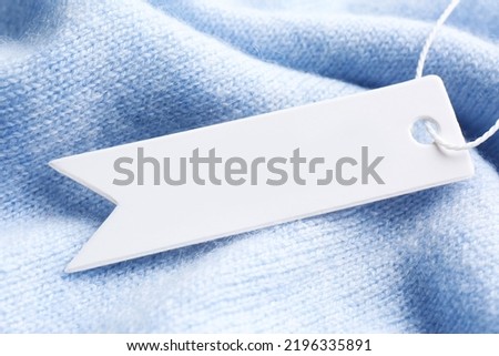 Tag with space for text on light blue knitted fabric, top view