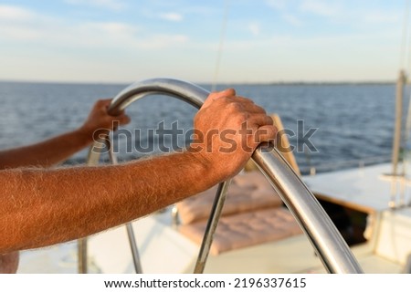 Male hands hold the steering wheel on the yacht. Travel by sea with adventures.