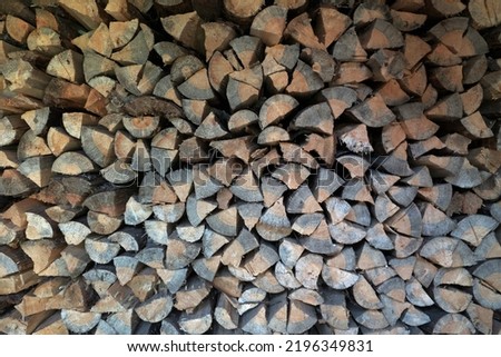 A woodpile of firewood lies in a pile, chopped for burning in the oven.Preparation for winter. A pile of logs for firewood. Background with firewood.Buying and selling firewood for winter
