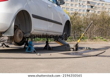 A tool for lifting a car over the road. Seasonal tire replacement on the street. Background picture.