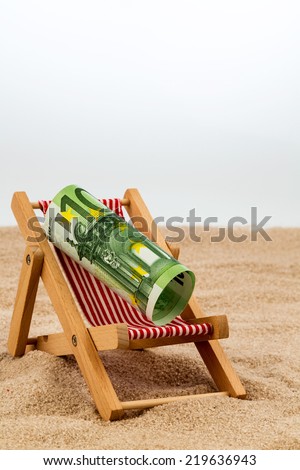 a deck chair with a euro banknote. symbol photo for saving on holiday and when traveling