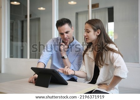 Young attractive woman and young man are interacting with the mobile tablet in cafe.